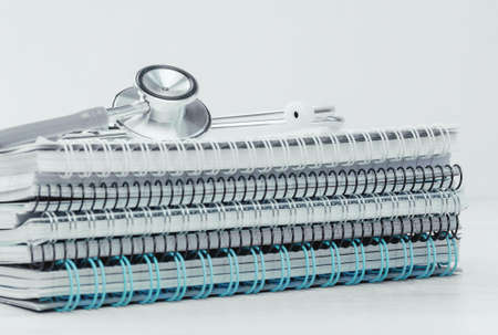 Medical or healthcare concept. stethoscope on top of pile of spiral notepads. Medical study or...