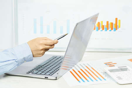 Hand pointing at laptop screen with statistics chart. Finance and business concept. financial...