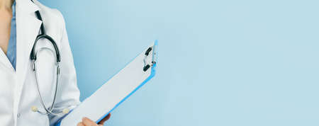 Female caucasian doctor in white uniform holding a blank clipboard. Medicine. Blue web banner. Copy...