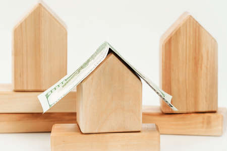 Wooden building blocks houses close up with dollar bill roof. Mortgage rates and loans. Real estate...