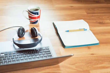 Headphones and laptop for remote working or studying at home with UK flag mug notepad and snacks at...