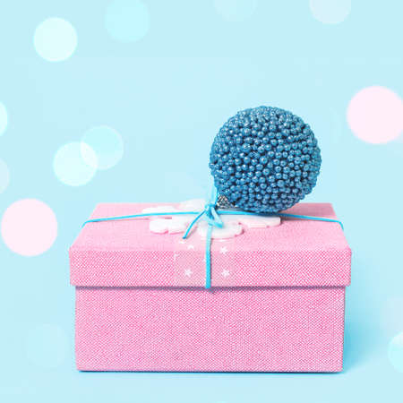 Christmas pink gift box with blue bauble on blue. Merry Christmas or Happy New Year greeting card...