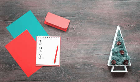 Numbered Christmas wish list on desk with Christmas tree. Copy space