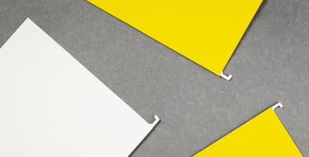 White and yellow hanging files lay flat on gray background. Banner with copy space and mockups for text. Office supplies or noticeの写真素材