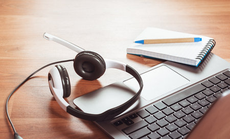 Headphones and laptop for remote working or studying at home with notepad and snacks at home desk or floor. Distance learning English language or freelance work concept or isolationの写真素材