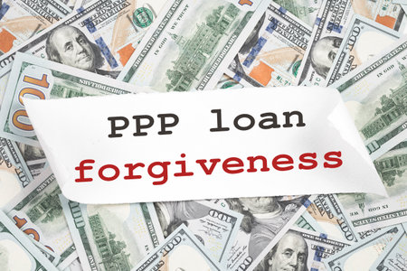 PPP loan forgiveness text note on hundred dollar bill notes. Cash Money background. Small business Paycheck Protection Program. Banking and finance conceptの写真素材