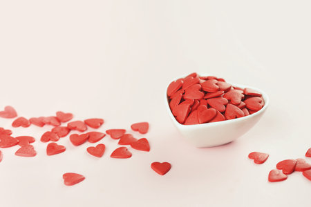 Heart shaped red sprinkles in a white bowl , festive love gift and Valentine's Day concept. banner mockup. Small hearts. Selective focusの写真素材