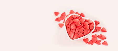 Heart shaped red sprinkles in a white bowl , festive love gift and Valentine's Day concept. banner mockup. Small hearts. Selective focusの写真素材