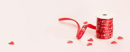 A roll of red gift ribbon with sprinkles hearts for St Valentines day or 14 February. Minimal banner with copy spaceの写真素材