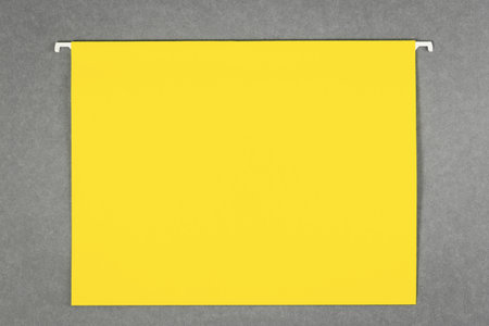 One bright yellow hanging file lays flat on gray background. Banner with copy space and mockups for text. Office supplies or noticeの写真素材