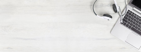 Laptop. keyboard and headphones on grey desk and plain wooden background banner. Helpdesk or call center headset. Distant learning or working from home, online courses or support center concept.の写真素材
