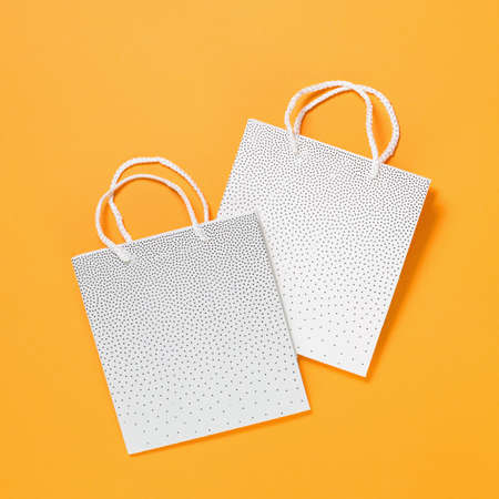 Two blank mockup white shopping bags on orange background. Shopping or sale conceptの写真素材