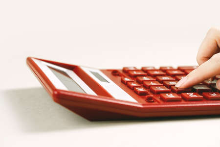 Finance and business concept. Female small business. Hand with red calculator on desk. Accounting budgeting or market analysis. Home finance. copy space. loans reportingの写真素材