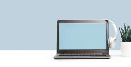 Laptop. Mockup screen and headphones on white desk and plain background banner. Distant learning....