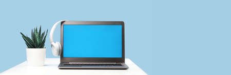 Laptop. Mockup screen and headphones on white desk and plain background banner. Distant learning. working from home, online courses or support minimal concept. Helpdesk or call center headsetの写真素材