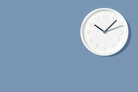 Plain wall clock on polka dot brown gray and blue background banner. Two o'clock. Close up copy...