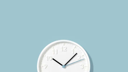 White plain analogue wall clock on trendy pastel blue background. Five past ten oclock. Close up...