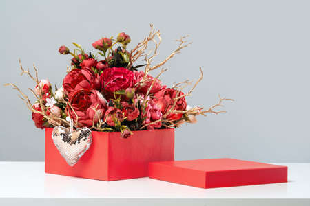 Red gift box of rich rose flowers bouquet with golden branches and heart. Mothers or International Women's Day, 8 March, 14 February, St Valentines Day greeting card. Wedding and thank you. Copy spaceの写真素材