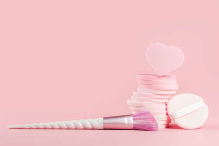 Tender pink monochrome feminine makeup tools and accessories. Unicorn blush brush and stack of sponges on candy pink. Birthday beauty cosmetics blogger advert background concept. Copy spaceの写真素材