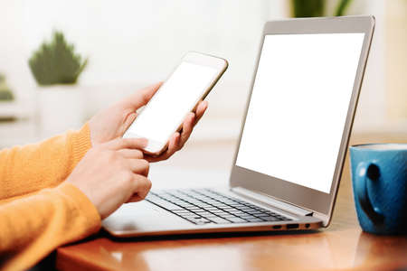Close up banner of a woman using a mobile phone smartphone and laptop. Mockup white screens. Working...