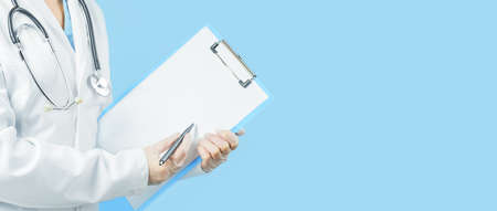 Female caucasian doctor in white uniform pointing at blank clipboard. Medicine. Blue web banner....