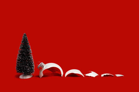 White broken glass bauble on red Christmas background with Christmas tree. Winter holiday season depression and stress, mental health problems. Shattered dreams. Copy space edgelessの写真素材