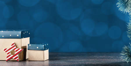 Christmas ornaments. Two gift boxes under Christmas tree. Star with stripes. Happy new year greeting card. Copy space banner. Blue lightsの写真素材