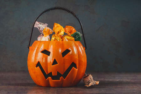 Orange halloween Jack-o-Lantern pumpkin with candies and spider webs. Trick or treat. happy halloween party decoration banner. copy spaceの写真素材