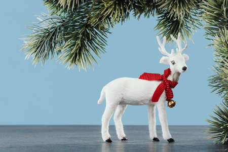 White toy Christmas reindeer on baby blue background with pine branch. Merry Christmas and Happy New Year seasons greetings cardの写真素材