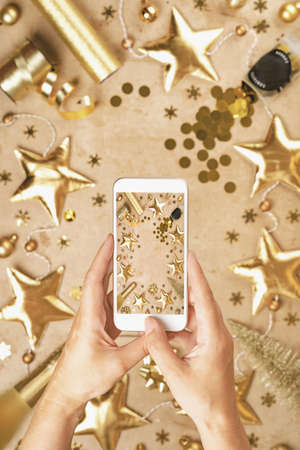 Taking photo with mobile phone. Merry Christmas and Happy New Year rich golden background and...