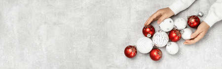 Hands holding Red and white Christmas baubles on grey flat lay. Merry Christmas and Happy New Year...