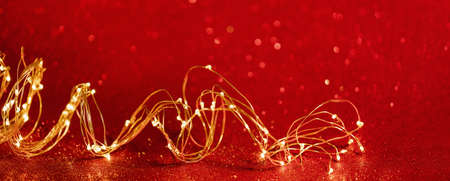 christmas background. Twisted golden xmas lights wire on sparkly festive red background. Copy space....