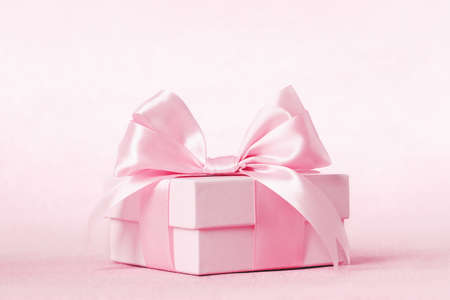 Pinkgift box with shining pink ribbon bow on pink background. Gift or holiday concept. Mothers Day, birthday wedding or St Valentines day banner with copy space. Minimal monochromeの写真素材