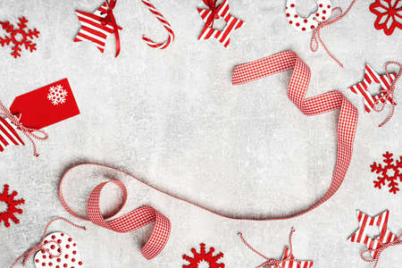 Red and white assorted Christmas ornaments with checked ribbon flat lay on gray. Merry Christmas and...