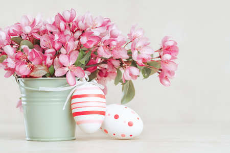Spring blooming tree branches and easter eggs in a vase on pastel backgroundの写真素材