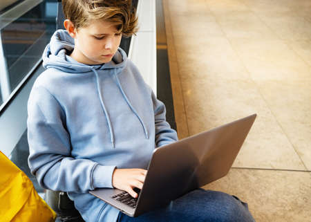 Child boy with a laptop studying or entataining at public spaceの写真素材