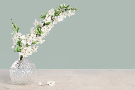 Spring blooming tree branches in a vase on tender green blue