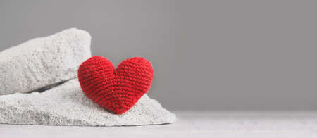 Big knitted red heart on gray stones banner