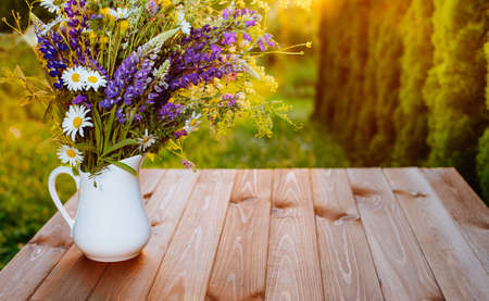 Beautiful summer flowers in a vase on a wooden patioの写真素材