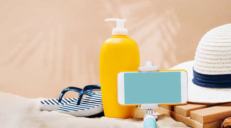 Striped marine flip flops, sunscreen lotion on a sandy beach
