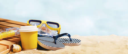 Striped marine flip flops, sunscreen lotion on a sandy beach