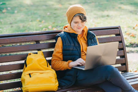 Child boy with headphones studying at home with laptop