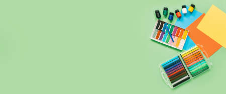 Color paper, paint and school stationery on green desk