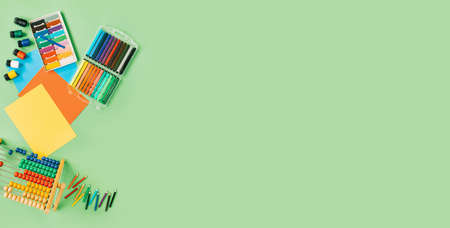Color paper, paint and school stationery on green desk