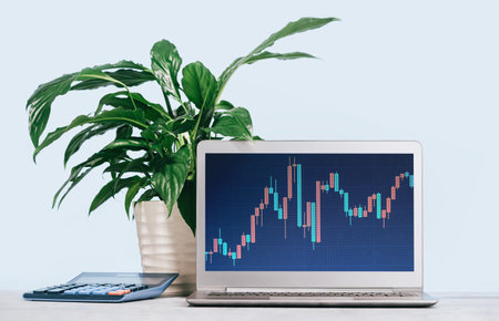 Laptop with finance graphs on white desk