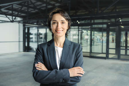 Successful confident smiling middle-aged caucasian business woman looks into camera folding hands in jacket. Confident look. Leader. Self-made woman. Senior managerの写真素材