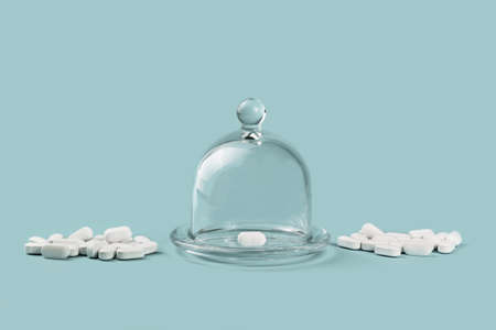 many white tablets on table and one unique in glass dome container. Healthcare and medicine concept...