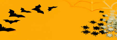 Several black vampire bats in line and spiders on orange cracked background. Happy Halloween craft banner with copy space. Selective focus. Minimalの写真素材