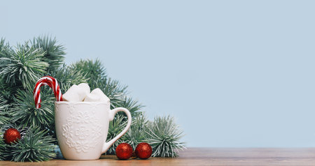 Christmas tree branch. Baubles. Hot chocolate mug with marshmallow. Christmas and New Year banner. Candy sticks. Copy space side viewの写真素材