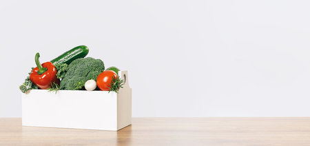 Fresh green and red vegetables in a box on a wooden table. Banner with copy space. Green vegetarian...